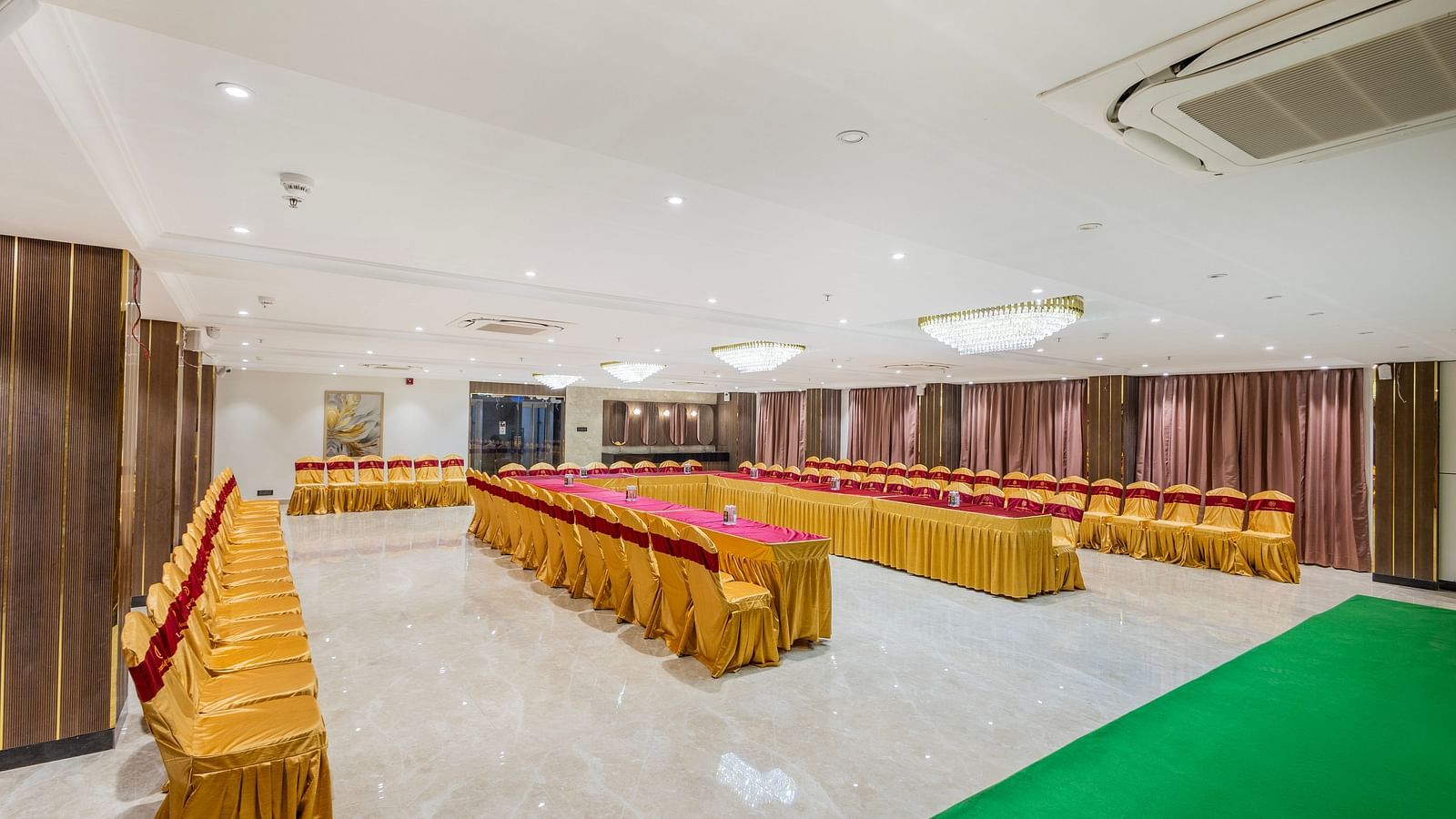 Lemonridge Hotels, KPHB | Banquet hall with an aisle runner, leading to a decorated stage. Chairs line the sides.